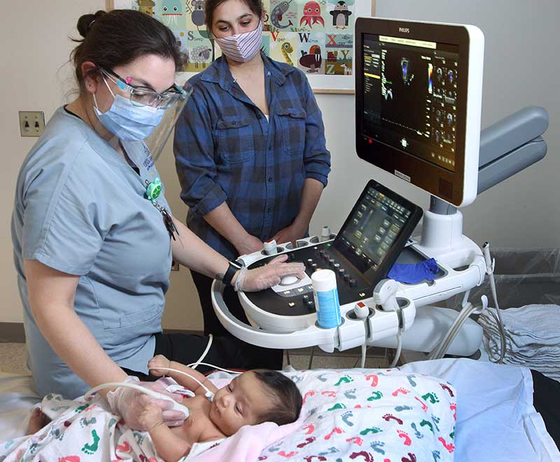 A nurse monitors a baby's heart while a mom watches