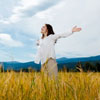 Woman standing in field with arms open