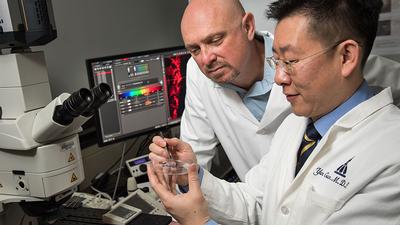 Gene Fridman and Yun Guan examine a prototype of a device that delivers direct current safely.