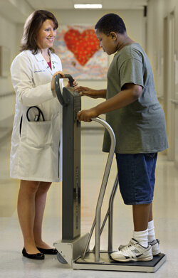 adolescent patient being weighed by female physician
