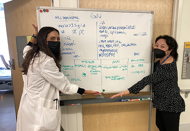 two students in front of a whiteboard in an inpatient clinic