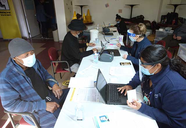 Community member being registered on a laptop by a clinic worker.