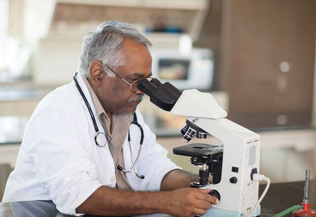Senior man performing research using a microscope