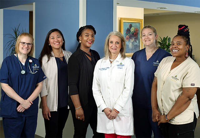 a group of nurses, doctors and other care team members smile