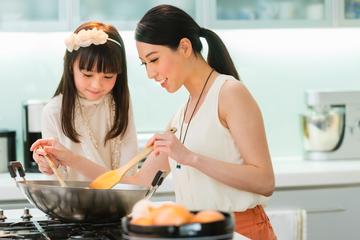 母亲和女儿在厨房炒菜。