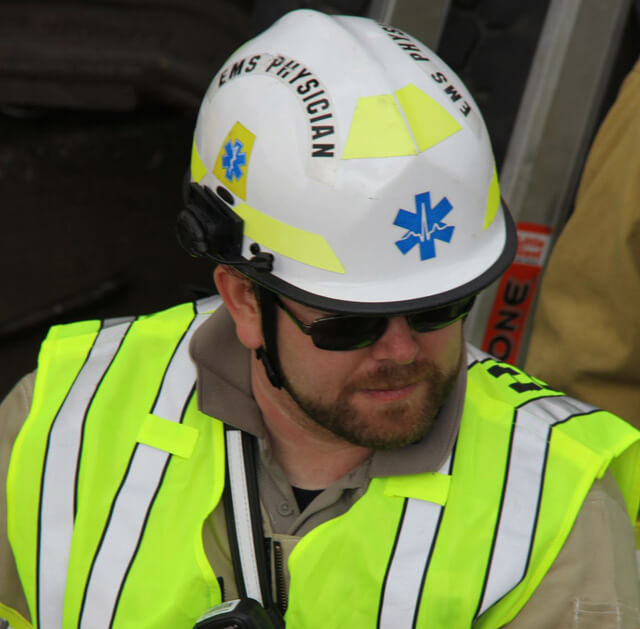 person with a beard in a hard hat and bright emergency outfit