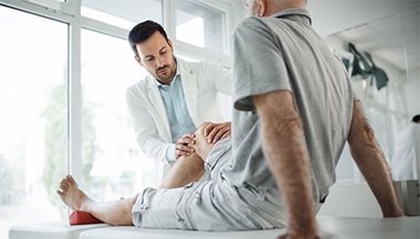 A physiatrist examining a patient's knee.